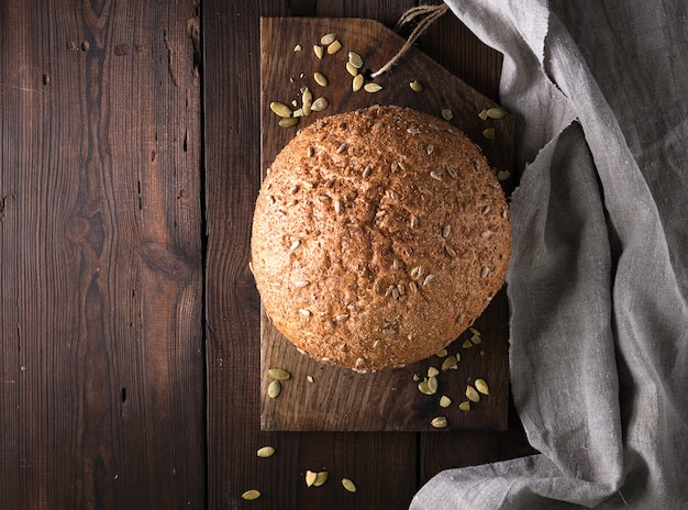 Gebackenes rundes Roggenbrot mit Sonnenblumensamen auf einer grauen Textilserviette