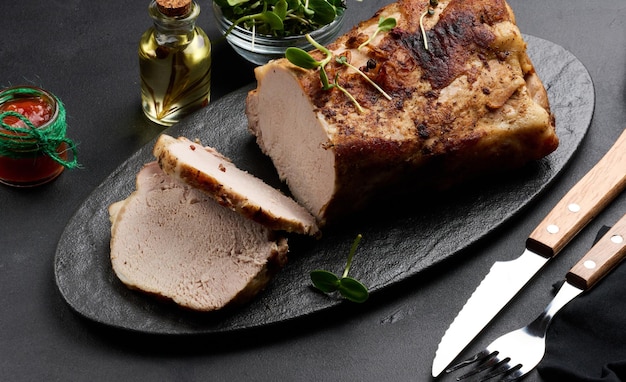 Gebackenes Stück Schweinefleisch-Balyk auf dem Tisch mit Gewürzen. In Stücke geschnittenes Filet