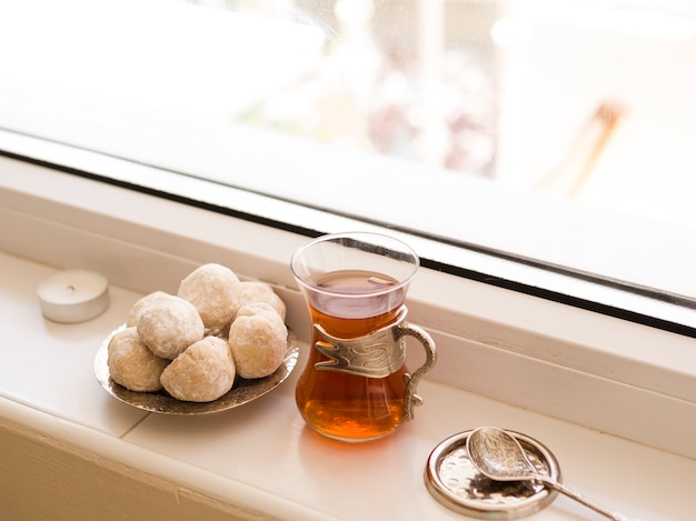 Foto gebäck, tee und löffel vor fensteranordnung