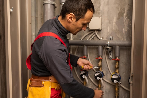 gebäude-, berufs- und personenkonzept - baumeister oder klempner, der mit wasserleitungen im heizraum arbeitet.