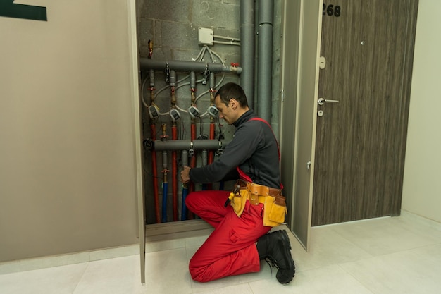 gebäude-, berufs- und personenkonzept - baumeister oder klempner, der mit wasserleitungen im heizraum arbeitet.