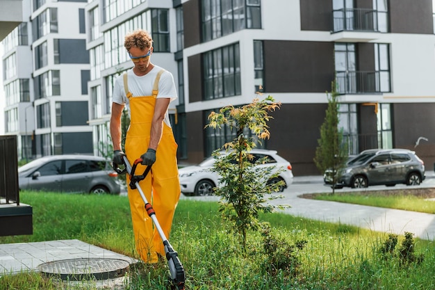 Gebäudehülle im Hintergrund Mann mähte das Gras mit Rasenmäher im Freien auf dem Hof