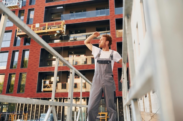 Gebäudehülle Junger Mann, der tagsüber in Uniform am Bau arbeitet