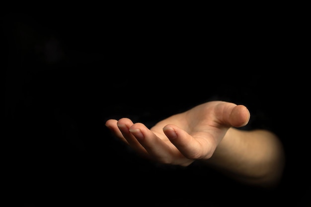 Geben der Handgeste leere Frauenhand auf einem schwarzen Hintergrundfoto