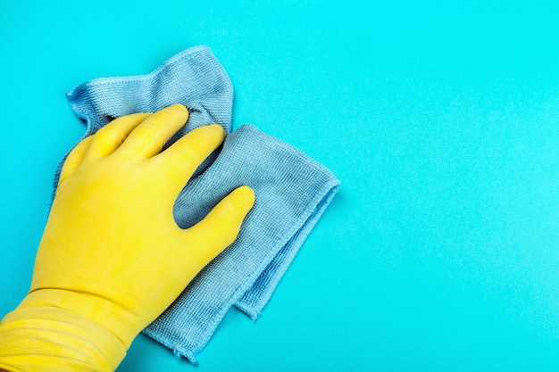 Geben Sie einen Gummihandschuh mit einem Lappen und Tüchern auf einem blauen Tisch ab