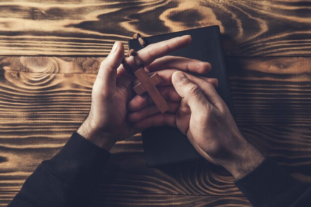 Gebetsmann-Handkreuz auf der heiligen Bibel auf Holztisch