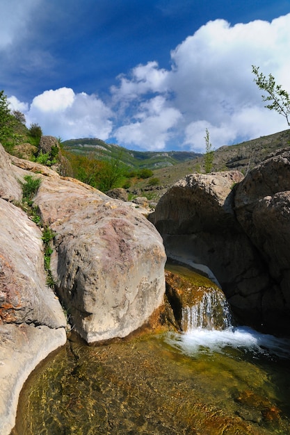 Gebirgsbach fließt auf den Felsen durch Steine. Gestein veränderte die Farbe durch Kontakt mit Wasser