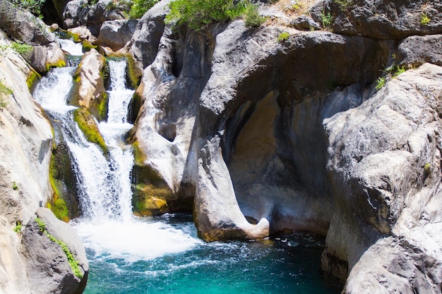 Gebirgsfluss mit türkisfarbenem Wasser und schönem Wasserfall