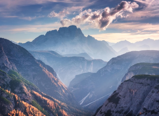 Gebirgsschlucht, beleuchtet von hellen Sonnenstrahlen bei Sonnenuntergang im Herbst in den Dolomiten, Italien. Landschaft mit Bergkämmen, Felsen, bunten Bäumen und orangefarbenen Grasalmenwiesen, goldenes Sonnenlicht in den Herbstalpen