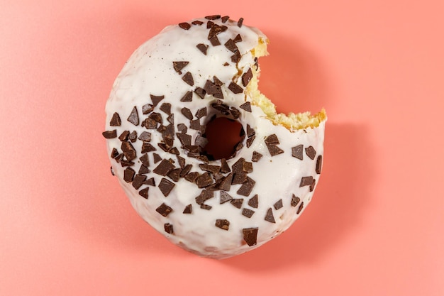 Gebissener leckerer Donut auf einem rosa Hintergrund Draufsicht