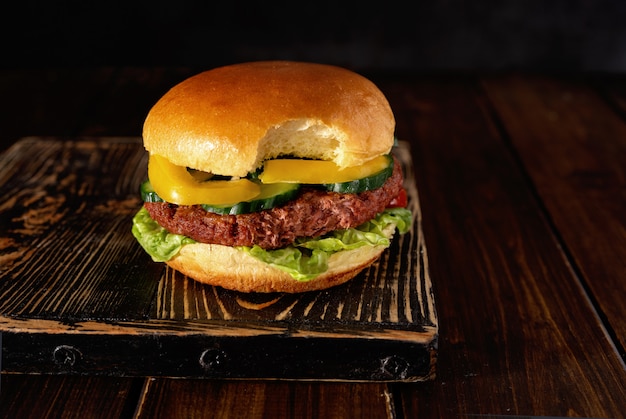 Gebissener vegetarischer Burger auf hölzernem Brett