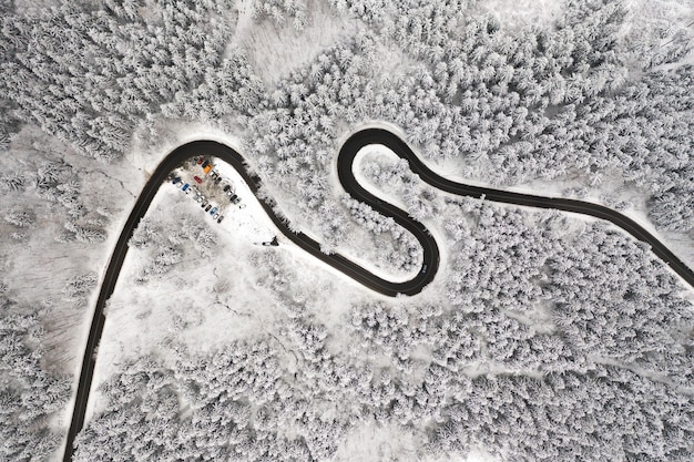 Gebogene S-förmige Straße in der Luftaufnahme des Winterwaldes.