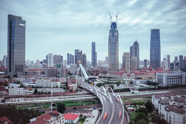 Gebogener Viadukt in Tianjin-Zugbewegungsunschärfe mit modernen Finanzgebäuden