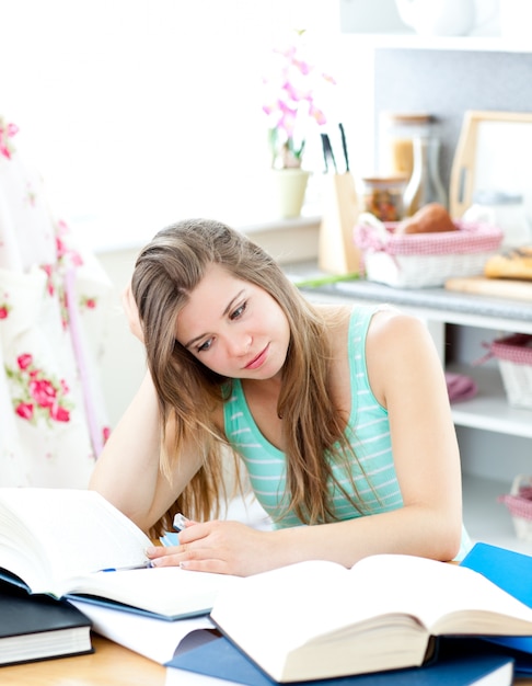 Gebohrter kaukasischer Student, der die Hausarbeit sitzt in der Küche tut