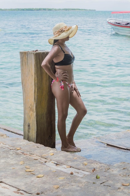 Gebräunte Frau in einem Badeanzug, die am Ufer des Piers am Meer wartet