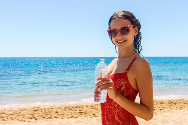 Gebräunte Frau Trinkwasser am Strand