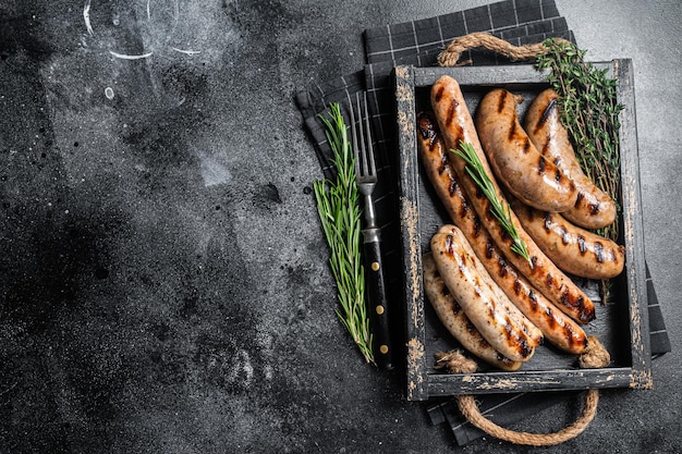 Gebraten auf einer Grillpfanne mischen Würstchen in einem Holztablett mit Kräutern Schwarzer Hintergrund Ansicht von oben Kopieren Sie Platz