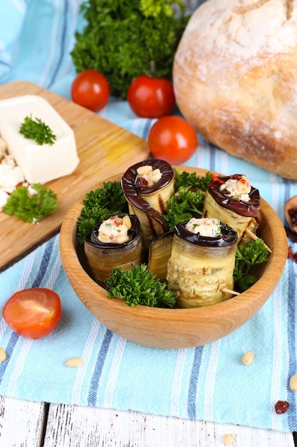 Gebratene Aubergine in einer Schüssel mit Hüttenkäsebrot und Petersilie auf Holzhintergrund