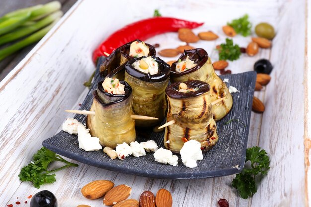 Gebratene Aubergine mit Hüttenkäse in einer quadratischen Platte auf Holzhintergrund