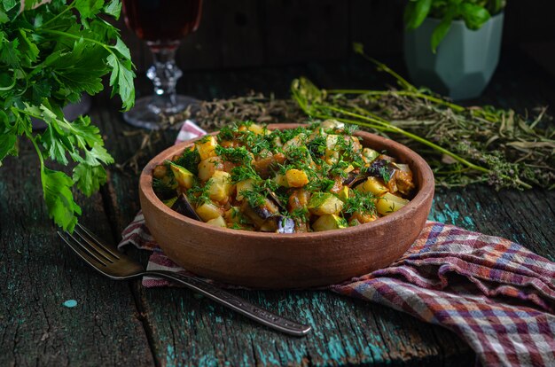 Gebratene Auberginen und Kartoffeln in einer Tonplatte (Ketsa). Hausgemachtes gesundes Essen im rustikalen Stil.