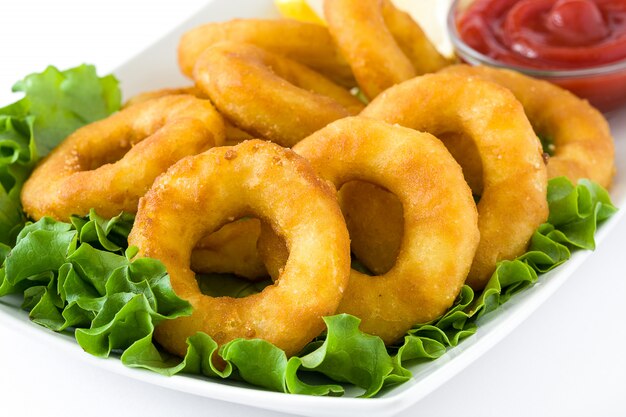 Gebratene calamariringe mit dem kopfsalat und ketschup lokalisiert auf weißer oberfläche