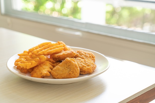 gebratene Chicken Nuggets mit Bratkartoffeln auf Teller