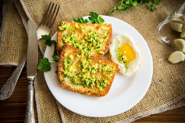 Gebratene Croutons im Teig mit Knoblauch und Kräutern auf einem Teller auf einem Holztisch