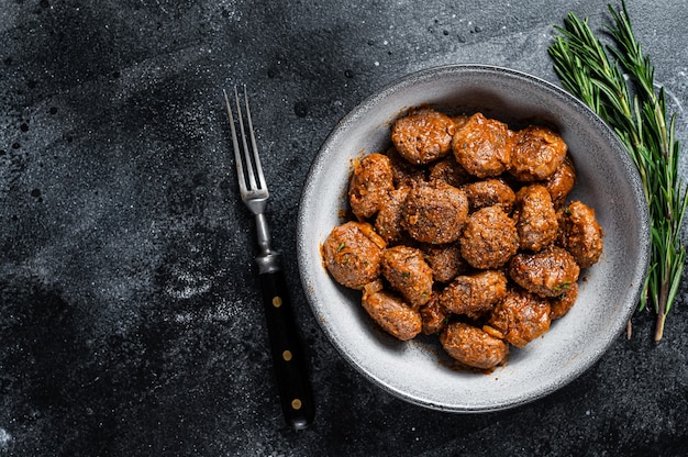 Gebratene Frikadellen in Tomatensauce aus Rind- und Schweinefleisch mit Rosmarin. Schwarzer Hintergrund. Ansicht von oben. Platz kopieren.