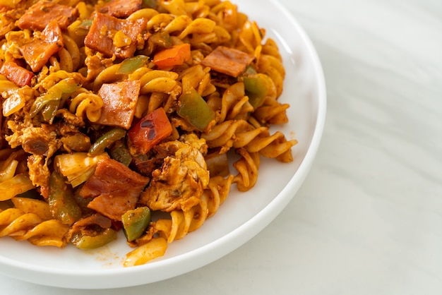 gebratene Fusilli-Nudeln mit Schinken-Tomaten-Sauce rühren