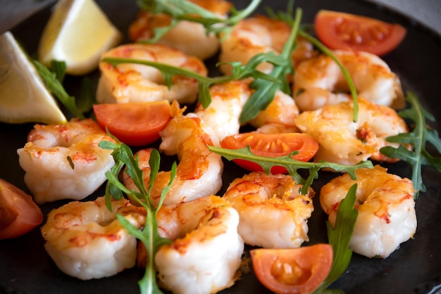 Gebratene Garnelen mit Tomaten und Rucola auf schwarzem Teller