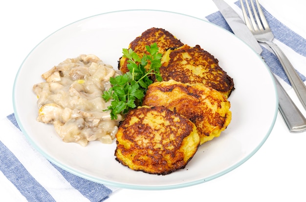 Gebratene geriebene Kartoffelpuffer mit Pilzsauce.