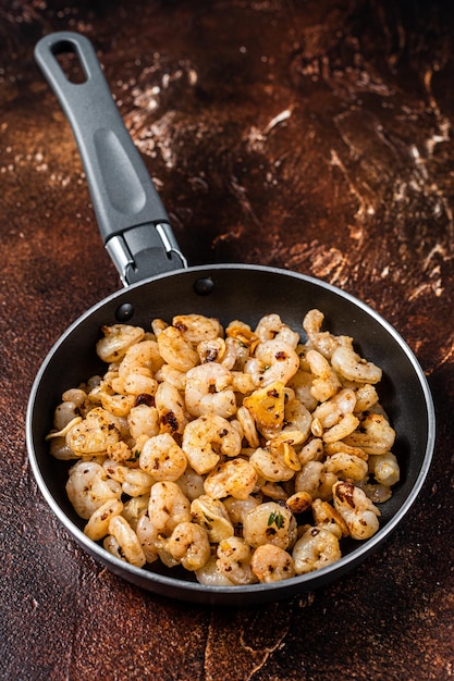 Gebratene geschälte Garnelen mit Knoblauch-Olivenöl in einer Pfanne Draufsicht auf dunklen Hintergrund