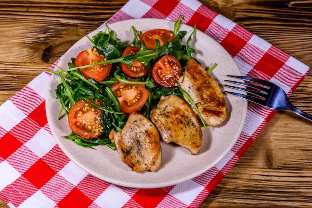 Gebratene Hähnchenbrust und Salat mit Rucola und Cherrytomaten in einer Keramikplatte