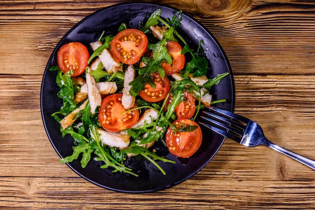 Gebratene Hähnchenbrust und Salat mit Rucola und Kirschtomaten in einer Keramikplatte Draufsicht