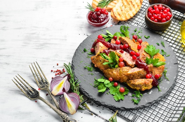 Gebratene Hühnerleber mit Preiselbeersauce und Preiselbeeren auf einer schwarzen Steinplatte Rustikale Ansicht von oben