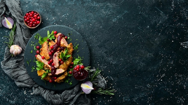 Gebratene Hühnerleber mit Preiselbeersauce und Preiselbeeren auf einer schwarzen Steinplatte. Rustikaler Stil. Ansicht von oben.