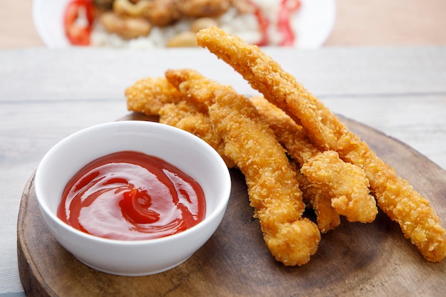 Gebratene Hühnerstreifen mit Tomatensauce auf Holztisch