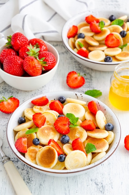 Gebratene Hüttenkäsepfannkuchen mit frischen Beeren auf einem weißen Teller