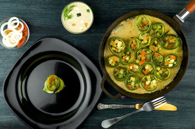 Gebratene junge geschnittene Zucchini in einer Pfanne auf einer dunklen Oberfläche