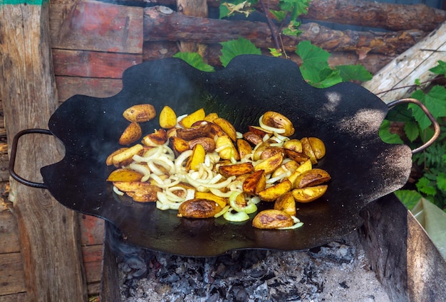 Gebratene junge Kartoffeln mit Zwiebeln auf dem Grill kochen.