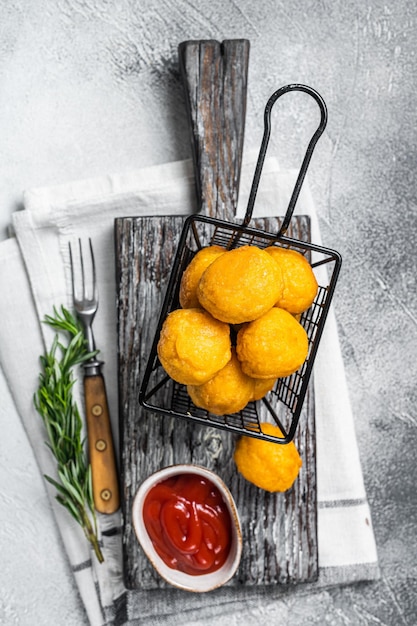 Gebratene Kartoffel-Käsebällchen-Kroketten mit Tomatenketchup, serviert in einem Korb Weißer Hintergrund Ansicht von oben