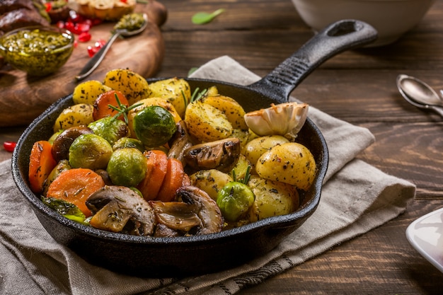 Foto gebratene kartoffeln mit gemüse und kräutern auf hölzernem hintergrund. gesundes nahrungsmittelkonzept.