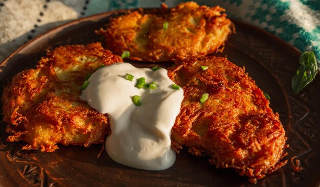 Gebratene Kartoffelpfannkuchen auf einer Lehmplatte Sauerrahm Frühlingszwiebeln Essen Kartoffelpfannkuchen Gericht