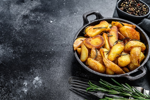 Gebratene Kartoffelschnitze, Pommes Frites in einer Pfanne. Schwarzer Hintergrund. Draufsicht. Speicherplatz kopieren