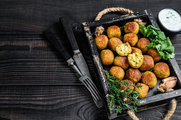 Gebratene Kichererbsen-Falafelbällchen mit Knoblauch-Joghurt-Sauce in einem Holztablett