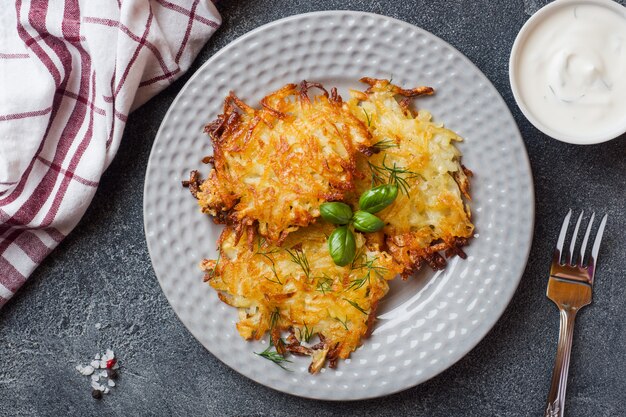 Gebratene Kuchen der zerriebenen Kartoffeln auf der Platte mit Soße, traditioneller Pfannkuchen boxty Raggmunk