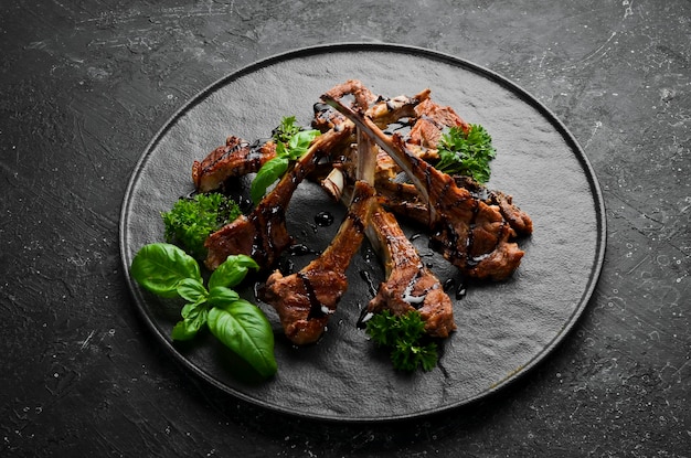 Gebratene Lammrippen mit Gewürzen und Knoblauch auf einem dunklen Küchentisch Rustikaler Stil Foto für den Katalog