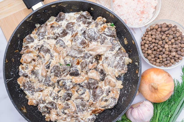 Gebratene Morchelpilze in Sauerrahmsauce in einer Bratpfanne