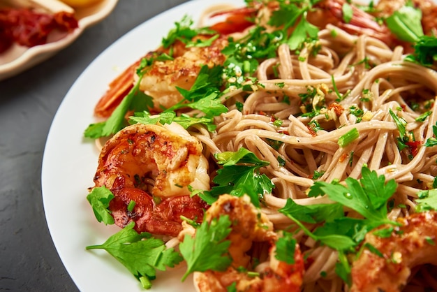 Gebratene Nudeln mit Garnelen und frischer Petersilie auf weißem Teller Soba mit Garnelen asiatischer Küche