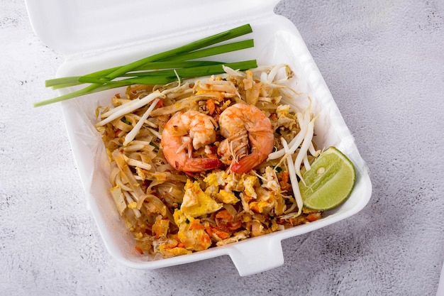 Gebratene Nudeln nach thailändischer Art mit Garnelen in Schaumstoffbox. Garnelenpaste Herzform auf Essen. Pad Thai mit Gemüse wie Frühlingszwiebeln, Limette, Sojasprossen und Tofu. beliebtes Streetfood von Thailand.